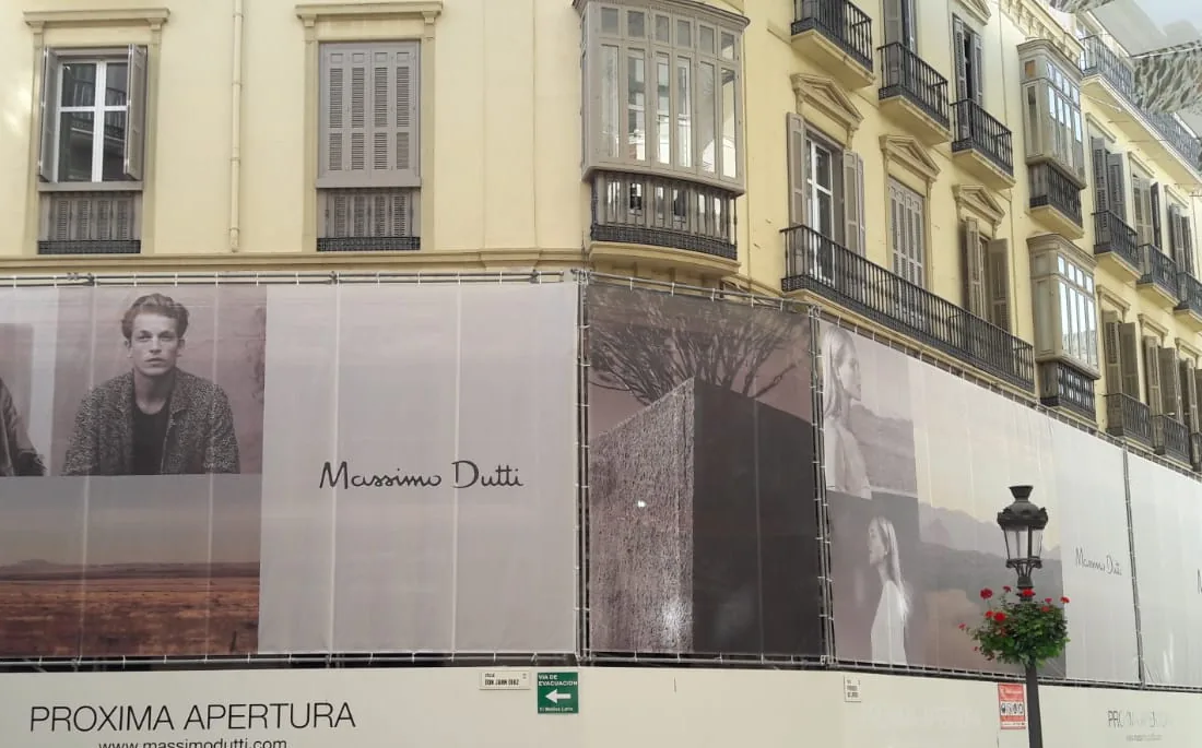 Lona publicitaria de gran formato cubriendo la fachada de un local en obras en una calle comercial