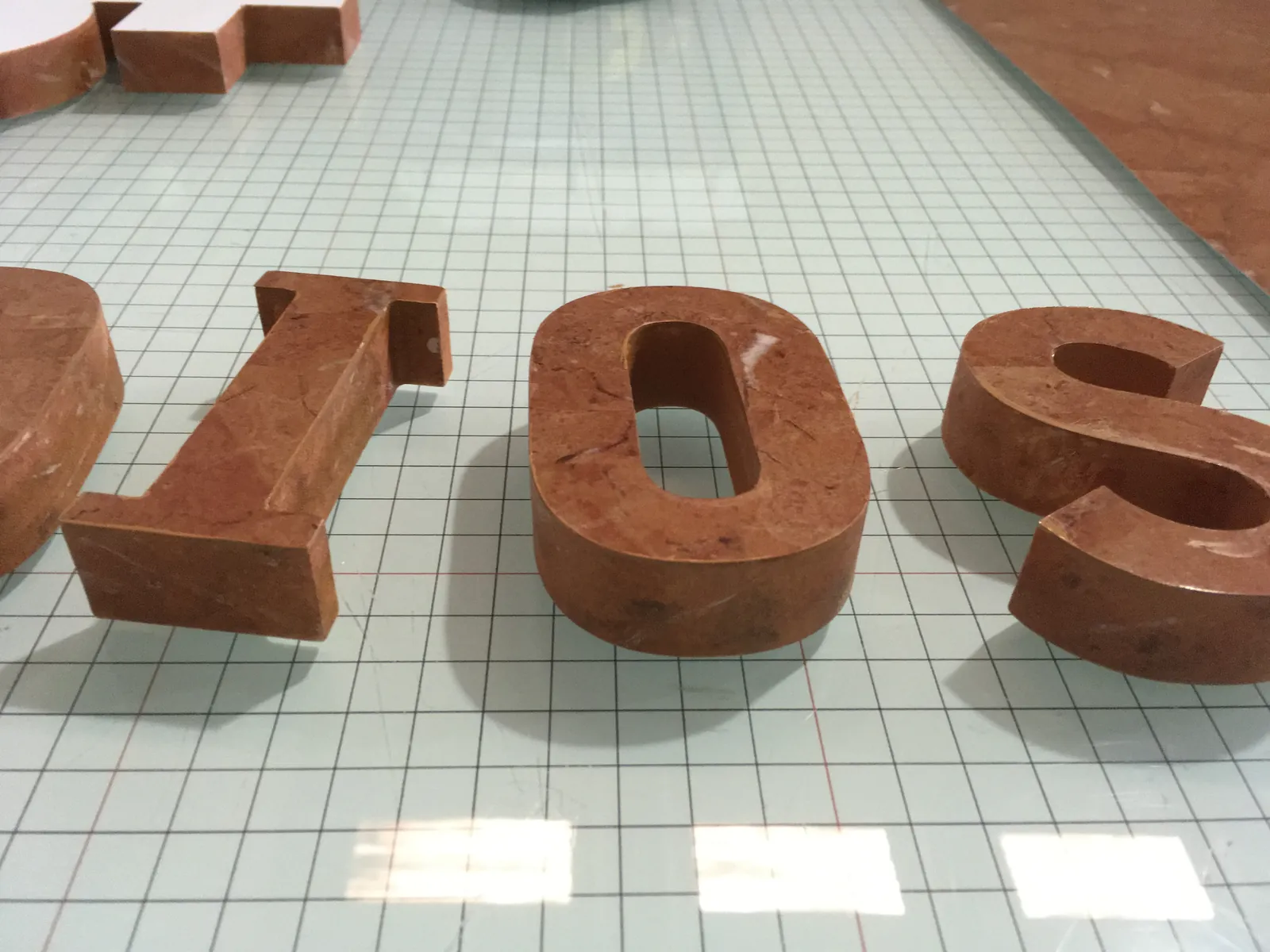 Letras corpóreas con acabado tipo mármol rojo pulido sobre la mesa de corte del taller