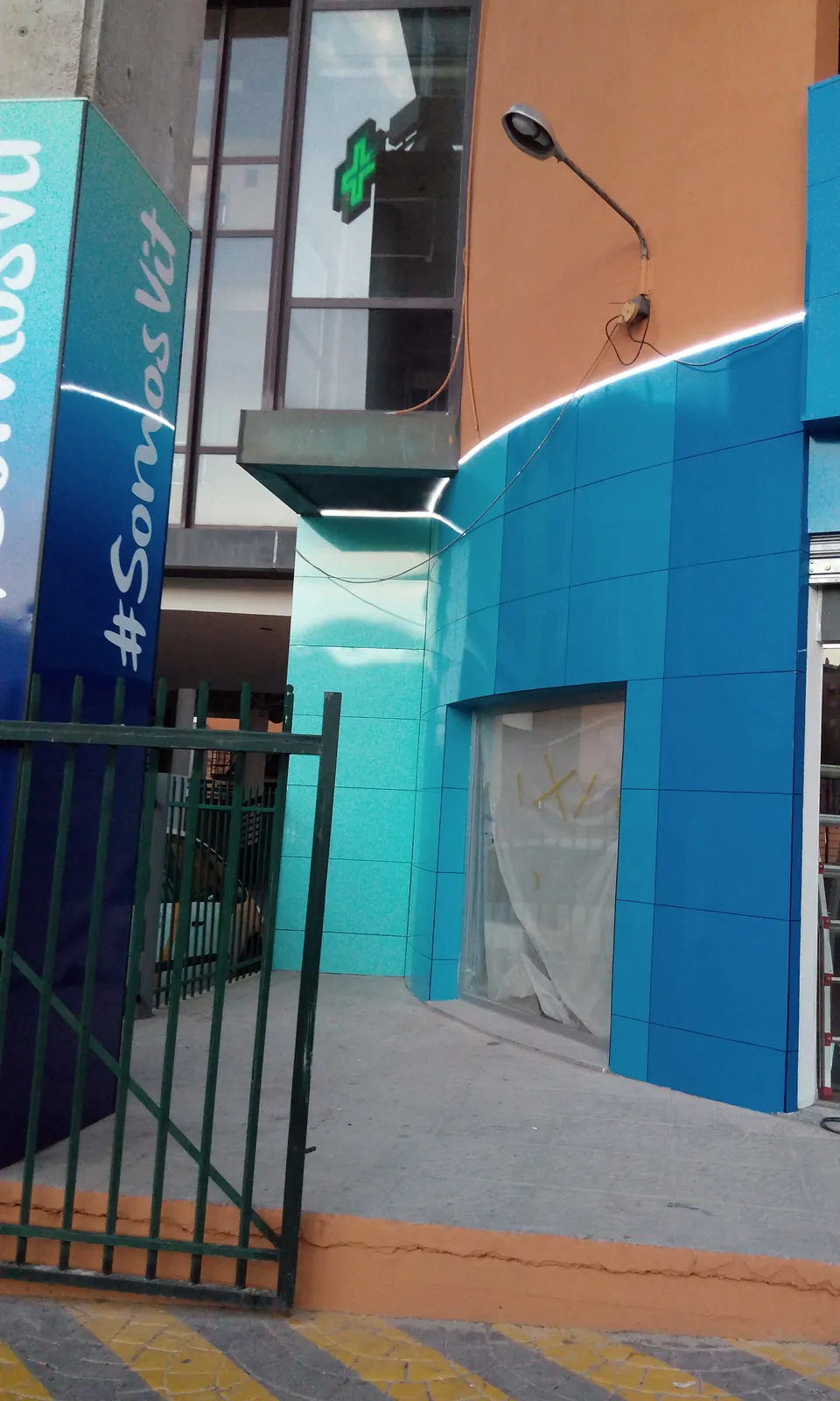 Fachada de clínica revestida en composite de aluminio en degradado azul, con tótem rotulado y tira LED perimetral encendida